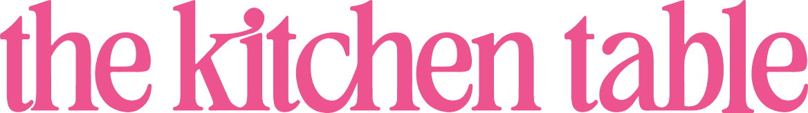 Stylized pink text on a white background reads “the kitchen table.”.